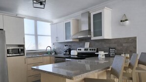 Een moderne keuken met een centraal eiland, inbouwapparatuur en een ontbijtbalk.
