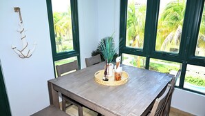 Een houten eettafel met stoelen, een sierplant en een aan de muur bevestigd anker.