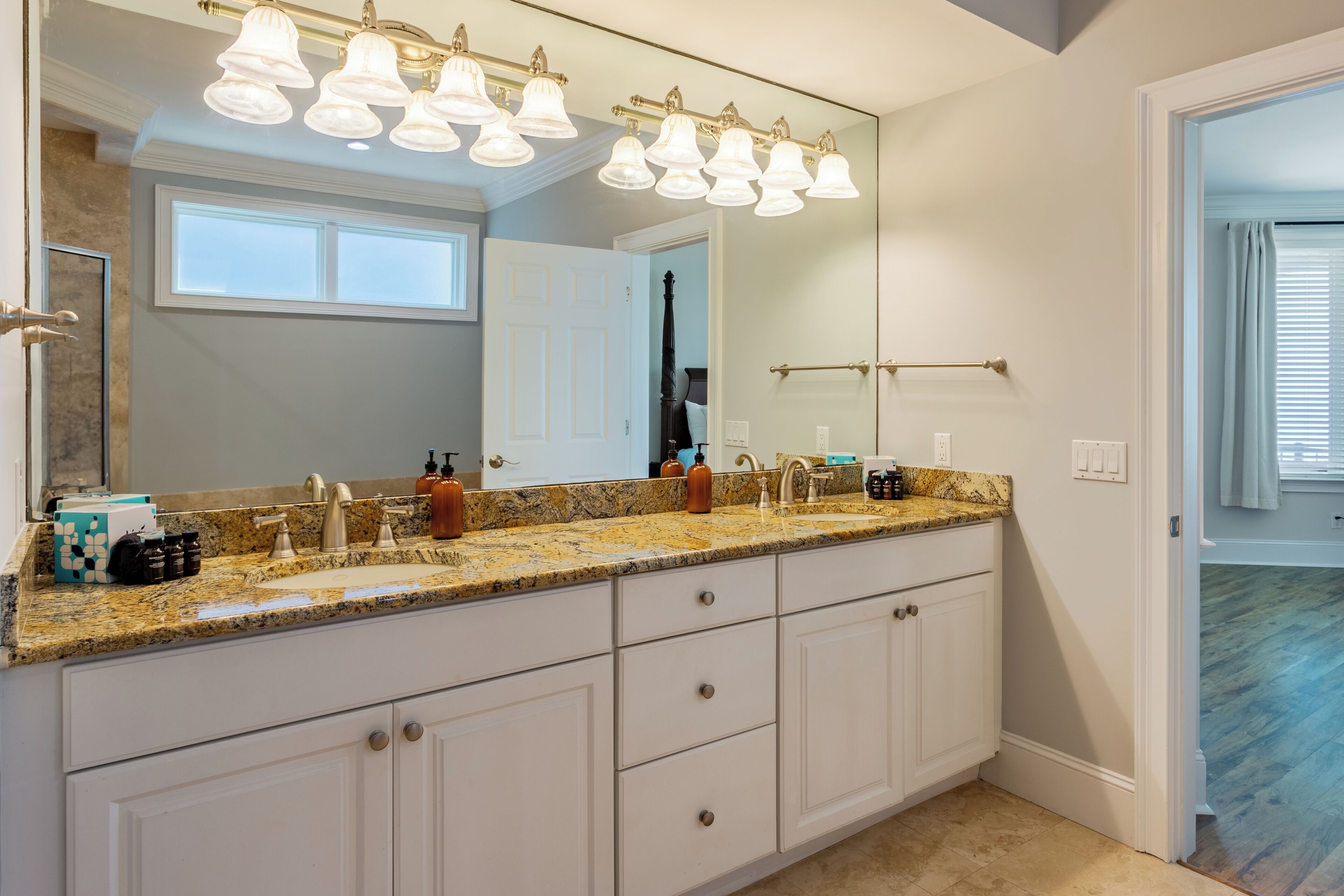 Un bagno con un ampio lavabo, due lavandini e uno specchio con luci soprastanti.