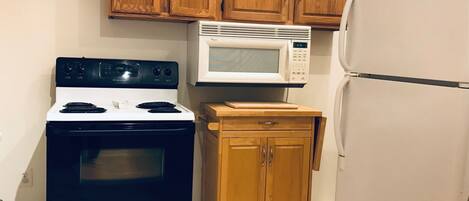 A kitchen with a stove, microwave, and refrigerator.