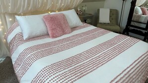 Quarto com uma cama grande, dossel, mesa de cabeceira, cadeira e abajur.