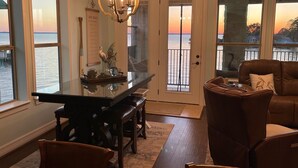 A dining area with a glass-top table, a chandelier, and a view of the water.