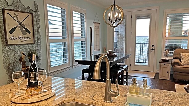 A kitchen with a granite countertop, stainless steel sink, and a dining area with a table and chairs.