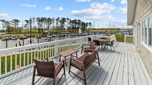 A wooden deck with outdoor furniture overlooking a marina with boats.
