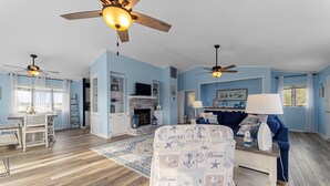 A living room with a fireplace, a dining area, and a blue color scheme.