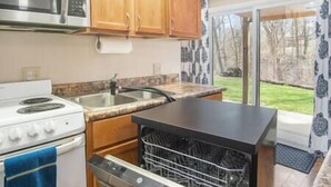 A compact kitchen with a stove, sink, and dishwasher. - Private Suite with Nature Views (Omaha)