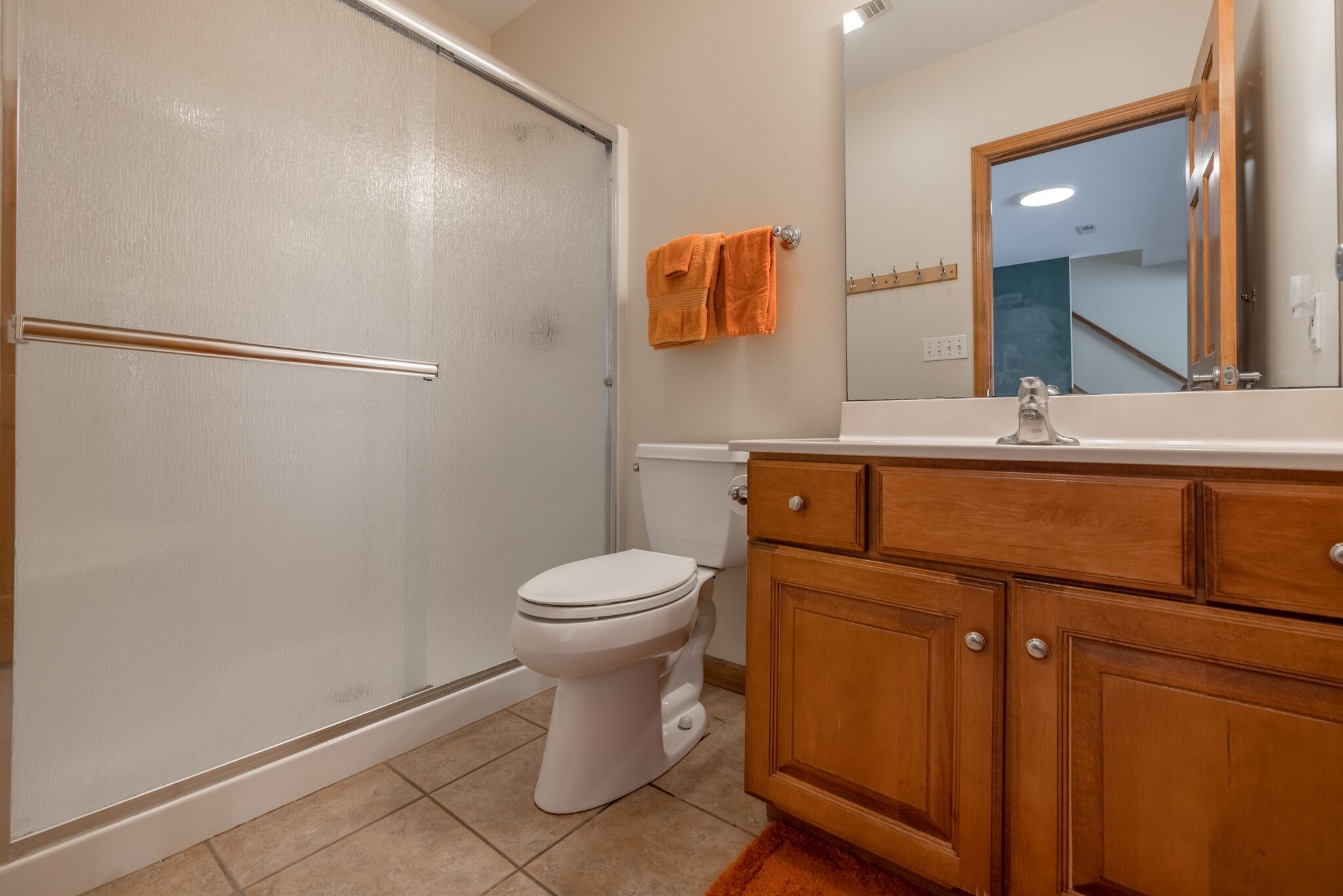 Un baño con inodoro, tocador de madera y espejo.