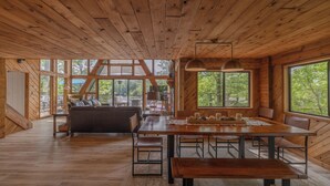 A wooden interior with a dining table, benches, and a sofa.