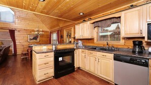 Een houten cabinemeubilair met een keuken, inclusief een fornuis, oven, vaatwasser en een raam met gordijnen.