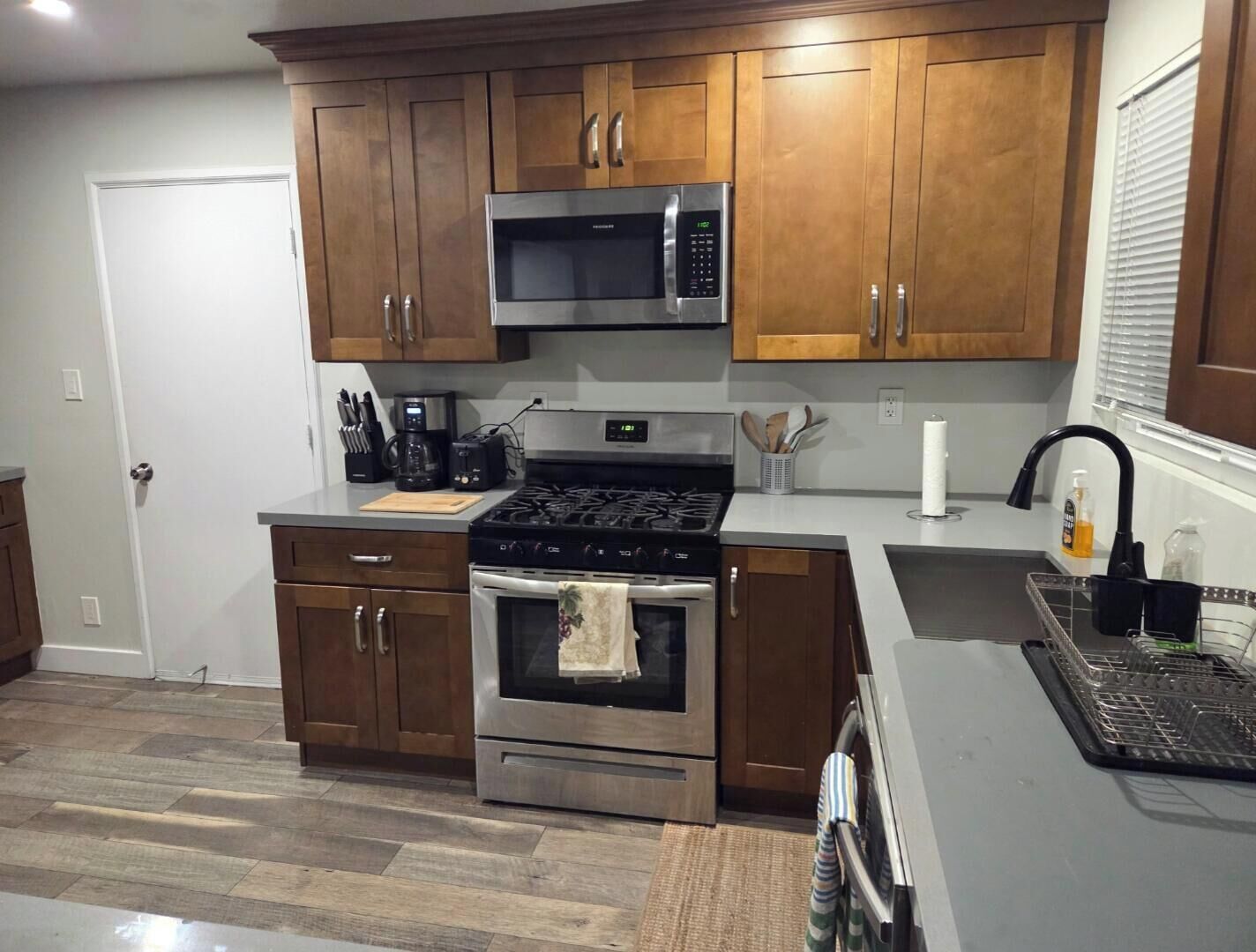 A modern kitchen with wooden cabinets, stainless steel appliances, a microwave, stove, and oven.