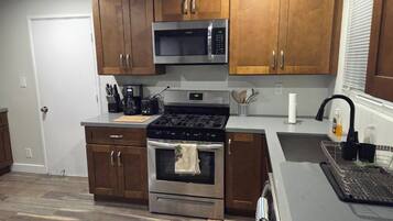 A modern kitchen with wooden cabinets, stainless steel appliances, a microwave, stove, and oven.