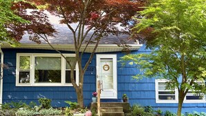 Une maison bleue avec des bordures blanches, une plaque portant le numéro 302 et un petit porche avec des marches.
