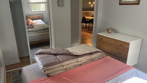 Une chambre à coucher avec un lit, une commode, un miroir et une fenêtre.