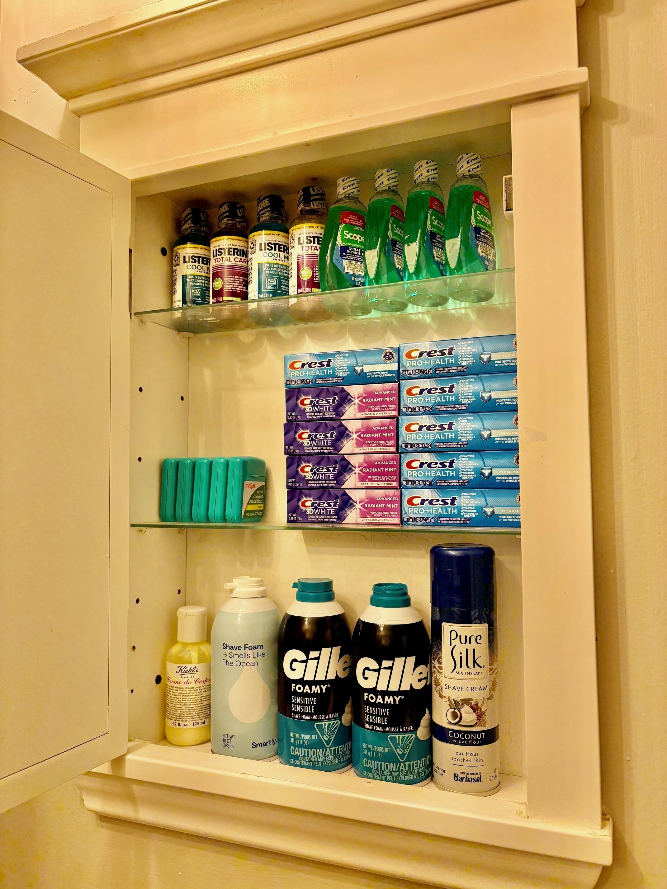 A bathroom cabinet with Crest Pro-Health toothpaste, Listerine mouthwash, Crest toothpaste, and Gillette shaving cream.