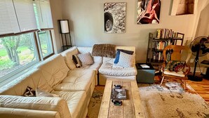 Un salon avec un canapé en cuir blanc, une table basse en bois et une bibliothèque.