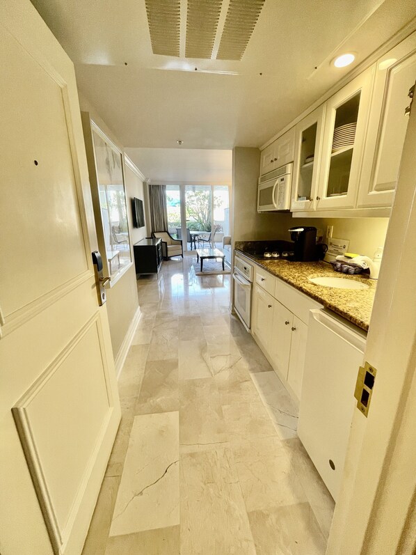 A kitchen with white cabinets, a granite countertop, and a view to the patio. - Suite on the beach, classy, large private patio (Marco Island)