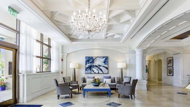 A spacious lobby with a chandelier, a large abstract painting, and a blue carpet leading to the entrance. - Suite on the beach, classy, large private patio (Marco Island)