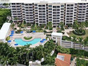 A high-rise hotel with multiple balconies, a swimming pool, and lush landscaping. - Suite on the beach, classy, large private patio (Marco Island)