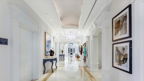 A spacious, well-lit hallway with a polished floor, flanked by white walls and framed artwork. - Suite on the beach, classy, large private patio (Marco Island)