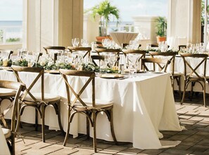 A banquet hall with round tables set for a formal event, featuring white tablecloths and wooden chairs. - Suite on the beach, classy, large private patio (Marco Island)