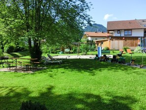 Um quintal bem cuidado com gramado, mesas de piquenique e área de estar externa.