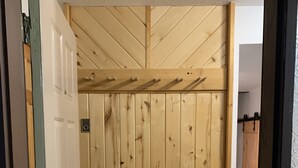 A wooden sauna room with a door, a bench, and a bench with hooks.