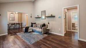 A spacious living room with a sofa, coffee table, and a dining area with chairs and a table. - The Red Door Retreat: Where Wellness Meets Southern Hospitality ✨ (Atlanta)