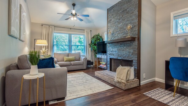 A modern living room with a fireplace, a sofa, a television, and a ceiling fan. - The Red Door Retreat: Where Wellness Meets Southern Hospitality ✨ (Atlanta)
