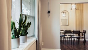 A modern interior with a dining area, potted plants by a window, and a minimalist wall clock. - The Red Door Retreat: Where Wellness Meets Southern Hospitality ✨ (Atlanta)