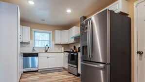 A modern kitchen with stainless steel appliances, white cabinets, and a wooden floor. - The Red Door Retreat: Where Wellness Meets Southern Hospitality ✨ (Atlanta)