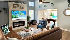 Una sala de estar con chimenea, ventilador de techo, televisor y mesa de billar.