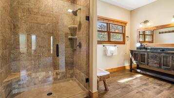 Une salle de bain moderne avec une douche à parois de verre, un plancher en bois et un meuble-lavabo avec un miroir.