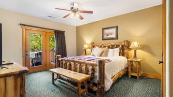 A bedroom with a wooden bed, two bedside tables with lamps, a ceiling fan, and a view of the outdoors through a sliding door.