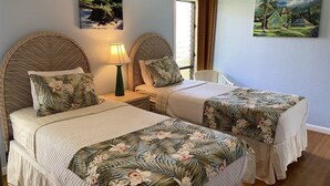 Une chambre avec deux lits, une table de chevet, une lampe et deux tableaux accrochés au mur.
