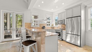 A modern kitchen with white cabinets, stainless steel appliances, and a central island with seating.