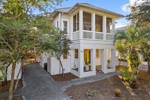 A two-story house with a covered porch, a brick pathway, and a well-maintained garden.