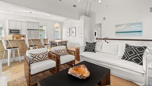 A spacious living area with a white sofa, wicker chairs, and a black coffee table.