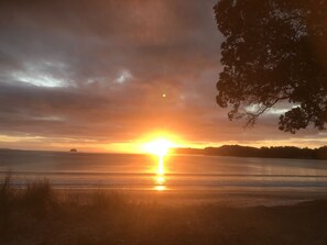 A sunset over a body of water with a tree silhouette on the right.