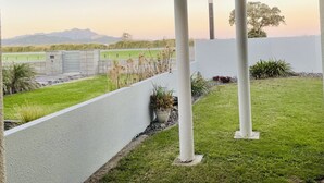 Un espacio al aire libre techado con vistas a un campo verde y montañas a lo lejos.