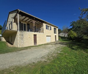 Ein zweistöckiges Steinhaus mit Balkon, Kiesweg und Rasengarten.