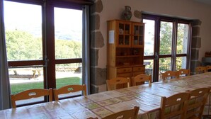 A dining area with a long table, wooden chairs, and a cabinet with glass doors.