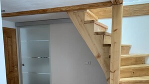 Ein Zimmer mit Holzboden, einem weißen Kleiderschrank und einer Holztreppe.