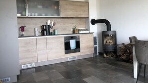 Eine moderne Küche mit Holzausstattung, einem eingebauten Ofen und einem Kaminofen.
