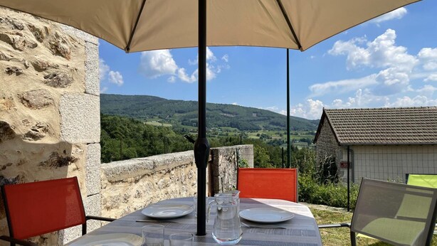 Ein Tisch draußen mit Blick auf eine Steinmauer und eine ländliche Landschaft.