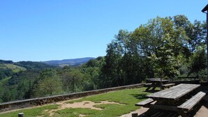 Un espace pique-nique équipé de bancs et offrant une vue sur un paysage vallonné.