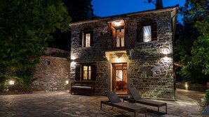 A stone building with a balcony, a wooden bench, and a lounge chair.