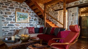 A cozy room with a stone wall, a wooden staircase, a red leather chair, and a chessboard on a wooden table.