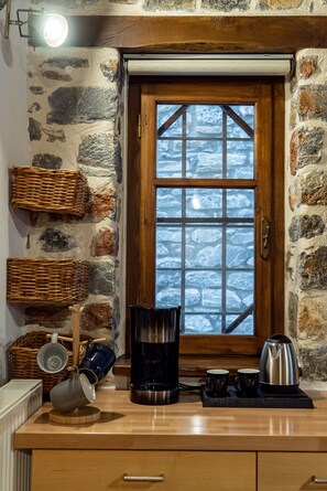 A kitchen with stone walls, a wooden door, and a view of snow outside.