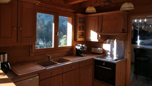 A wooden cabin kitchen with a sink, stove, and cabinets. - La Chevrière, beautiful log chalet, panoramic view, near Megève (Flumet)