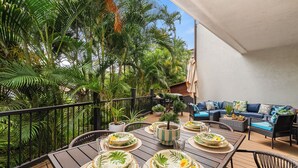 Comedor con una mesa dispuesta para cuatro personas, rodeado de exuberantes plantas tropicales.